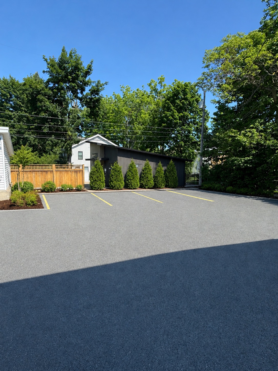 Freshly paved parking lot beside the property with privacy fencing and landscaping