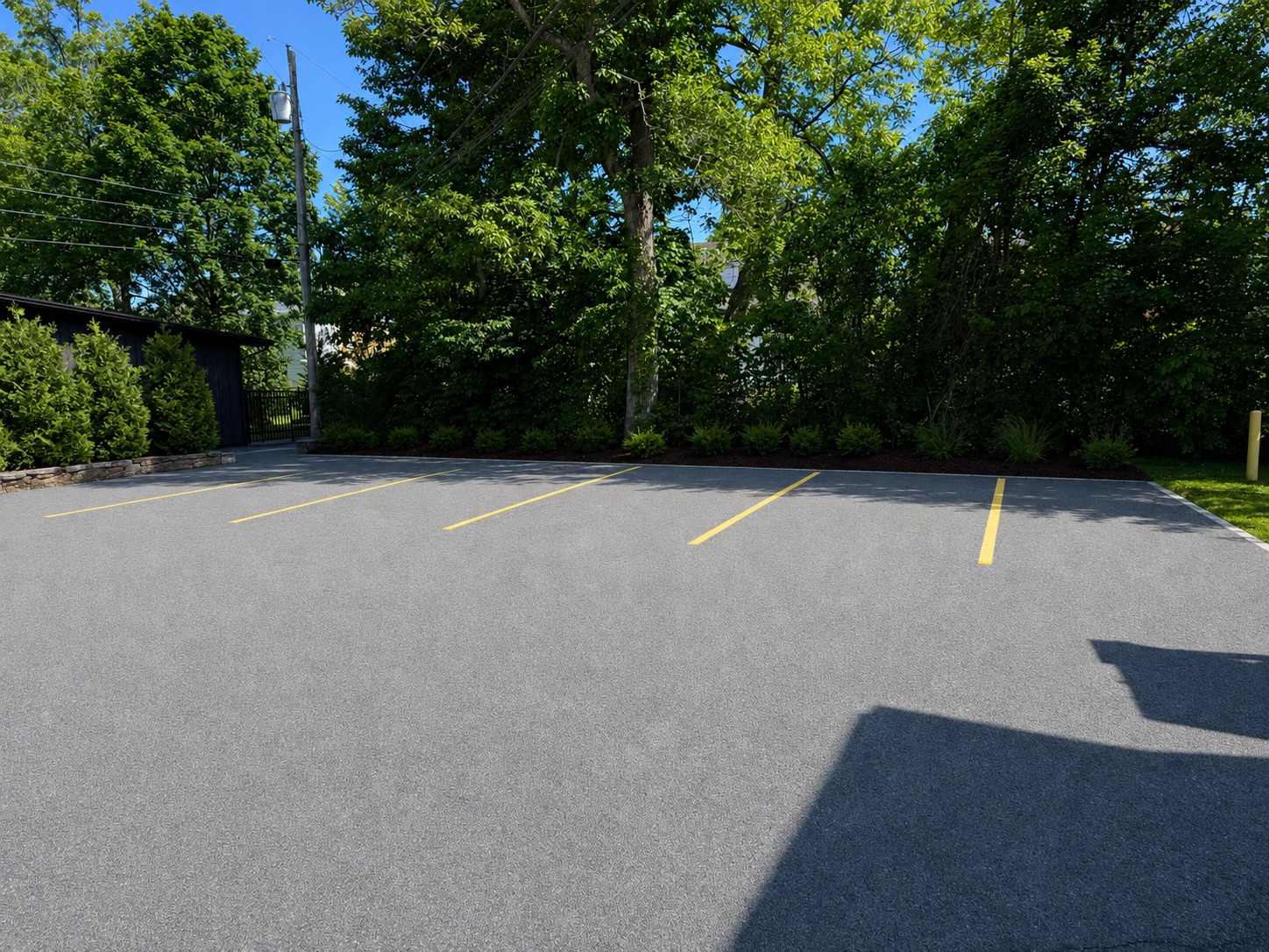 On-site off-street parking lot with marked spaces, bordered by mature trees
