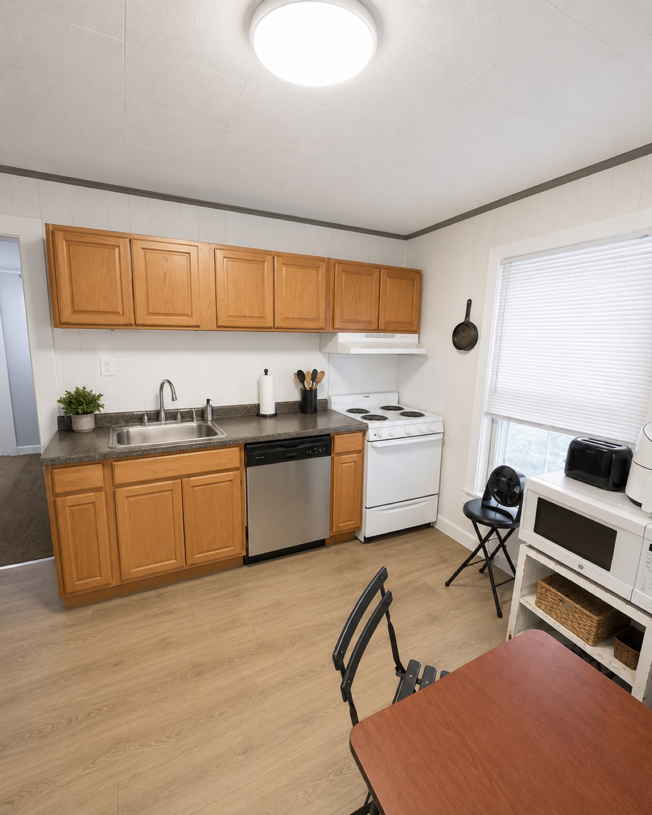 Second shared kitchen with wood cabinets, electric stove, and dishwasher