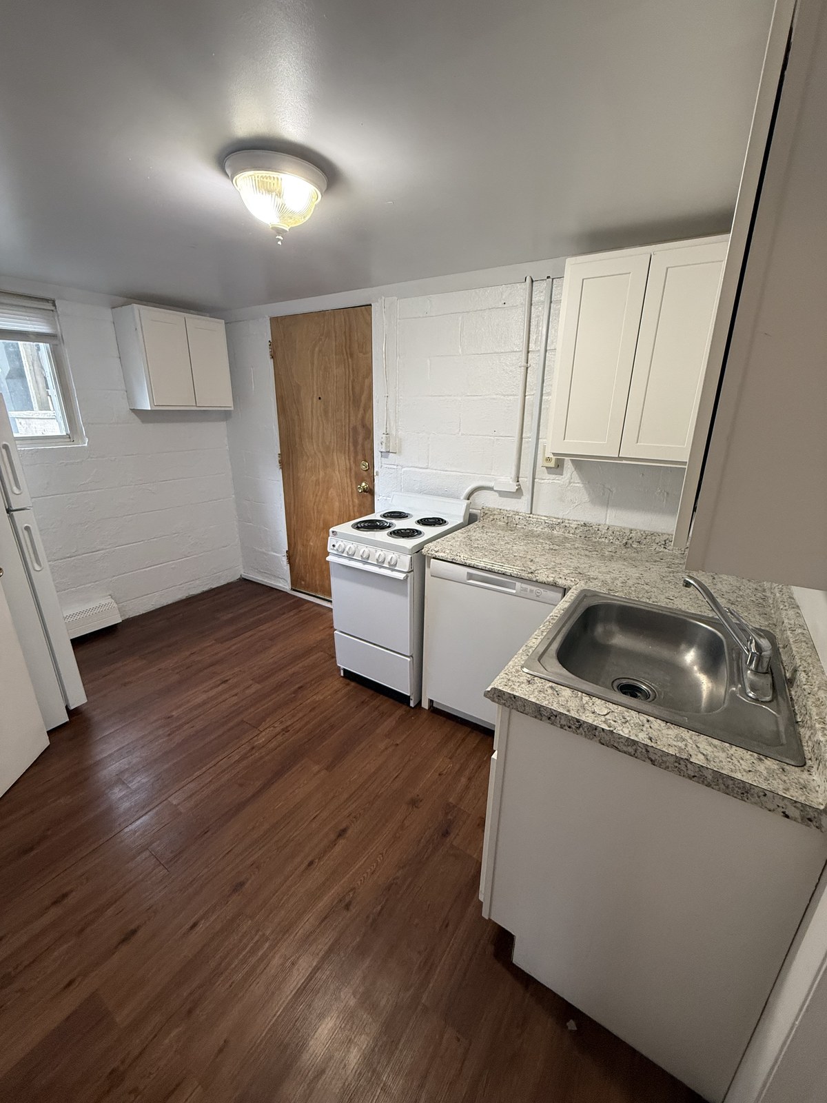 One-bedroom apartment kitchen with white cabinets and electric range